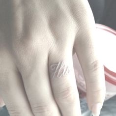 a person's hand with a ring on top of their thumb and the word love written in white ink