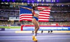 a woman holding an american flag on top of a track