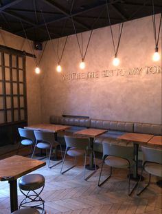 the inside of a restaurant with wooden tables and leather booths on the wall, along with hanging lights