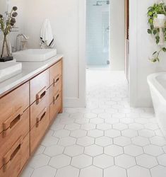 a bathroom with white tile and wooden cabinetry next to a bathtub in the corner