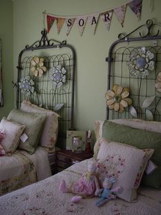 two twin beds in a bedroom with pink and green decor on the headboards,