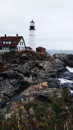 a lighthouse on top of a rocky cliff next to the ocean