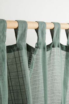 green curtains hanging on a wooden rod in front of a white wall