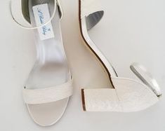 a pair of white high heeled shoes sitting on top of a white floor next to each other