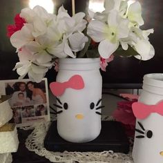 two vases with flowers and hello kitty cutouts on them sitting on a table