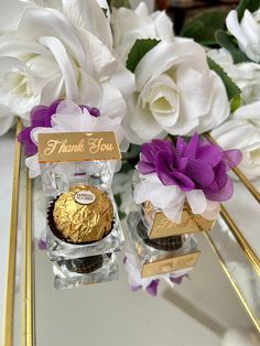 two vases filled with white and purple flowers on top of a table next to each other