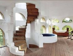 the interior of a house with wood flooring and white walls, arched windows, and circular staircase