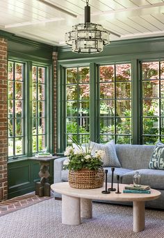 a living room filled with furniture and lots of green windows next to a brick wall