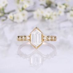 a close up view of a diamond ring on a white surface with flowers in the background