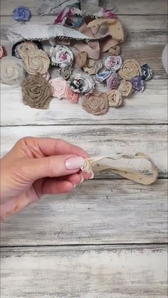 a hand holding a piece of fabric next to some scissors and buttons on a wooden surface