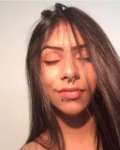 a woman with her eyes closed and nose piercing