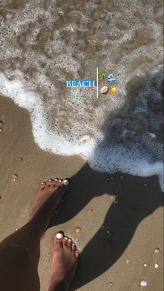 a person standing on the beach with their feet in the sand and water behind them