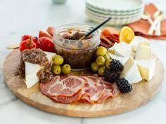 an assortment of meats and cheeses on a wooden platter