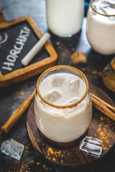 two glasses filled with liquid sitting on top of a wooden tray next to some cookies