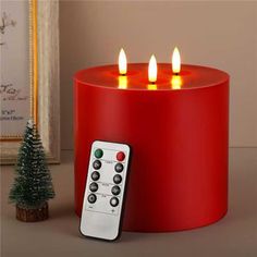 a remote control sitting on top of a red table next to a small christmas tree