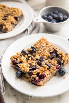 a bowl filled with granola and cherries on top of a wooden table next to a jar of jam