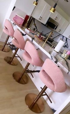 three pink chairs sitting in front of a counter