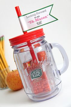 there is a jar with some candy in it and pencils on the table next to it