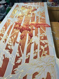 a painting is being worked on with gold foil and red flowers in the foreground