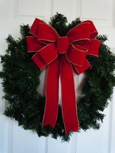 a wreath with a red bow hanging on the front door