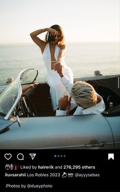 a woman in white dress sitting on the back of a car next to a man