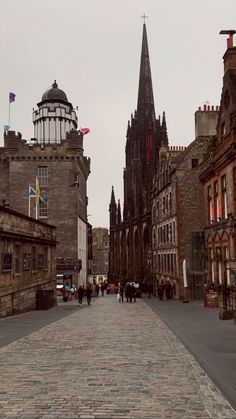 a cobblestone street lined with old buildings and tall spires in the background