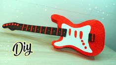 a red and white guitar shaped object sitting on top of a wooden table