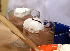 two desserts with whipped cream and chocolate pudding in bowls on a wooden table top