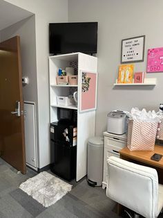 a room with a desk, refrigerator and other items on the wall in it's corner