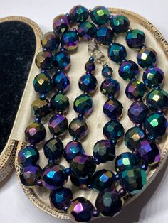 A Gorgeous Example of a Vintage 1940s Carnival or Peacock Faceted Glass Beaded Necklace 22" Long x 8mm Diameter Faceted Beads  Secure Screw Clasp Beautiful Displays of Blues Greens & Purples Presented in very good condition  Any boxes shown are for display purposes only & not included Vintage Faceted Beaded Necklace, Vintage Faceted Round Beads, Vintage Round Faceted Beads, Vintage Adjustable Faceted Beads, Vintage Formal Beaded Necklaces With Faceted Beads, Vintage Glass Faceted Beads, Vintage Glass Jewelry For Parties, Iridescent Vintage Jewelry For Parties, Vintage Single Strand Beads For Formal Occasions