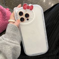 a person holding a cell phone case with two hello kitty buttons on the back of it