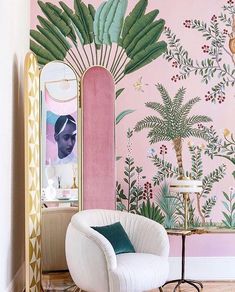 a chair and mirror in front of a pink wall with palm tree mural on it