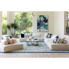 a living room filled with white couches and pillows on top of a blue rug