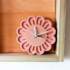 a pink clock sitting on top of a wooden shelf