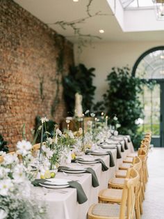 a long table is set with white and yellow flowers