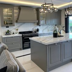 a kitchen with grey cabinets and marble counter tops