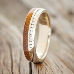 a wooden ring with white diamonds inlays on it sitting on a piece of wood