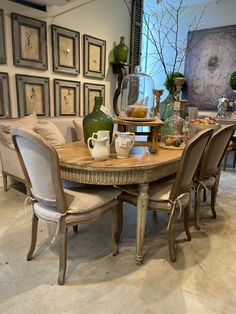 a dining room table with chairs around it and pictures on the wall in the background