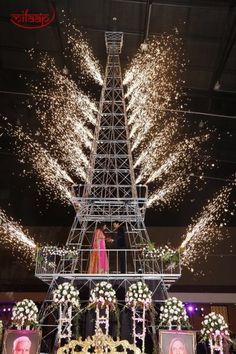 the eiffel tower is lit up with fireworks and flowers in front of it