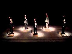 a group of people standing on top of stools in the dark with their hands up