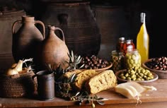 an assortment of food is displayed on a table with wine and olives in the background