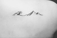 the back of a woman's shoulder with mountains on it