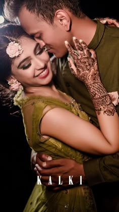 a man and woman embracing each other with their arms around each other, both wearing henna tattoos