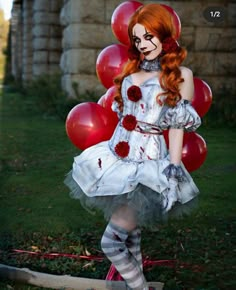 a woman dressed up as a clown with red hair and makeup, standing in front of balloons