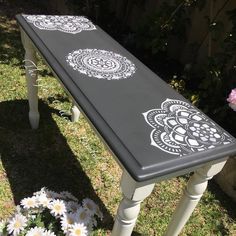 a black and white bench sitting in the grass with daisies on it's side