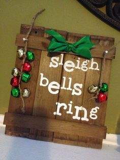 a wooden sign that says sleigh bells ring with ornaments hanging from the front