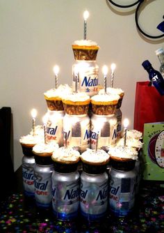 a cake made out of cupcakes with lit candles on top is surrounded by cans