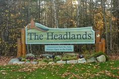 the sign for the headlands is in front of some trees and leaves on the ground