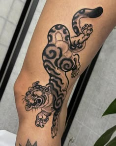 a black and white tattoo on the leg of a person with a tiger design on it