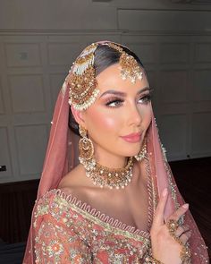 a woman in a pink dress with gold jewelry on her head and wearing a veil